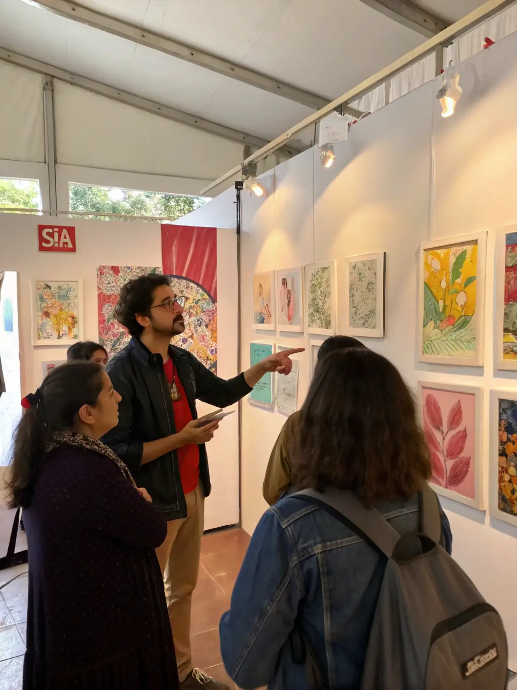 A dynamic image of an artist giving a talk at the Lurcy Les Arts exhibition, with an engaged audience listening attentively in a gallery setting.
